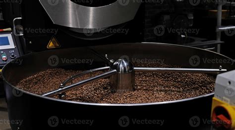 Granos de café tostado en la tolva de un molino de café