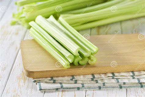 Imagen de tallos frescos de apio sobre una mesa de madera, destacando su textura y color verde vibrante.