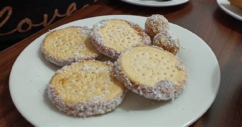 Cuadrados de galletas de chocolate con manjar y nueces decorados con líneas de chocolate y coco rallado.