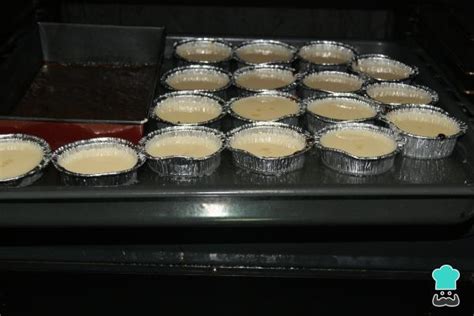 Bandeja de horno con moldes individuales de flan dentro de un baño maría, listos para entrar al horno.