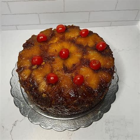 Imagen de una torta de piña recién desmoldada con rodajas de piña, cerezas y caramelo brillante.