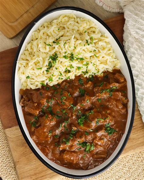 Plato de goulash humeante servido con spaetzle y pan