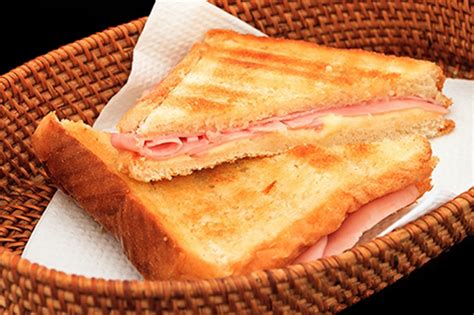 Fotografía de un sándwich caliente de jamón y queso con un toque de salsa de tomate