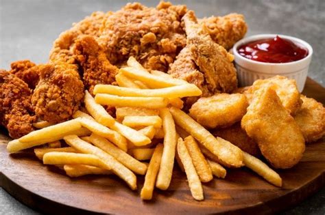 Imagen de una bandeja con pollo frito crujiente, papas fritas doradas y diversas salsas acompañantes