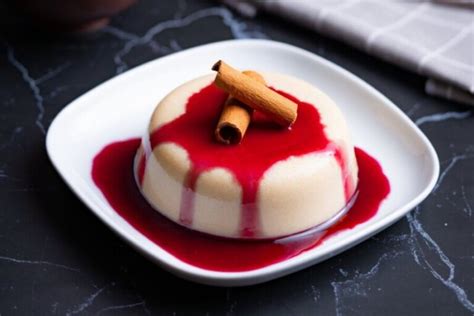 Fotografía profesional de un postre de sémola servido en plato, decorado con salsa de chocolate y trozos de mango fresco.