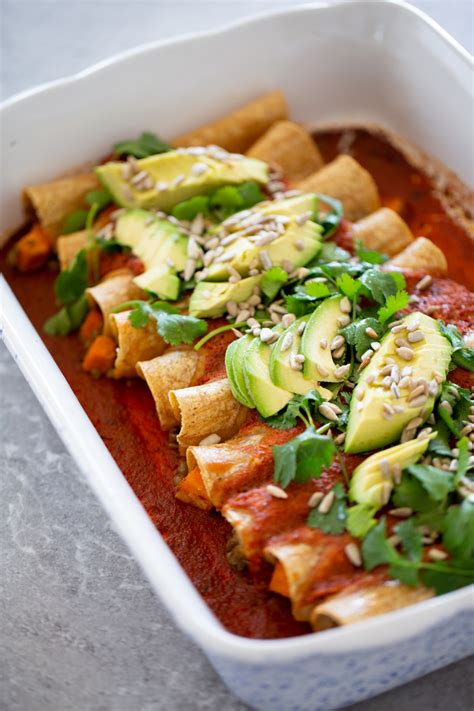 Imagen de una fuente de enchiladas veganas recién horneadas con salsa verde y cilantro fresco.