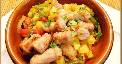 Fotografía profesional de un salteado de salchichas vienesas con pimientos y cebolla, servido en un plato hondo.