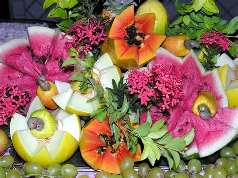 Primer plano de frutas frescas y flores vibrantes siendo ensambladas para un arreglo.
