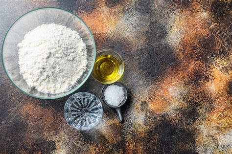 Esquema de los ingredientes principales: harina, sal, agua y aceite sobre una mesa de trabajo.