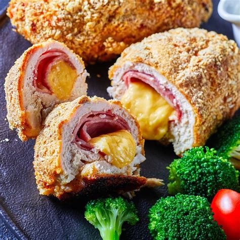 Pechugas de pollo rellenas de jamón y queso fritas, mostrando el interior fundido.