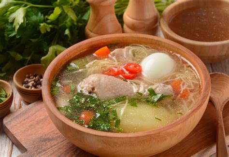 Plato de caldo de gallina criolla servido con huevo, papa y cebolla china