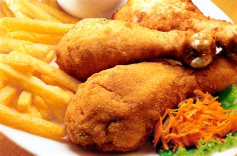 Plato servido de pollo apanado con papas doradas al horno y vegetales frescos
