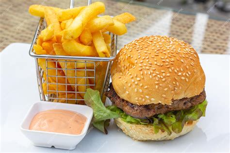 Plato de hamburguesa gourmet con papas fritas y salsas