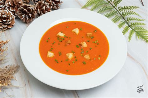 Sopa de tomate y pimiento cremosa, servida en un bol rústico con hierbas frescas