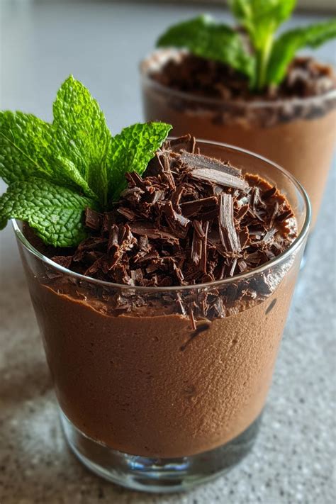 Primer plano de una copa de mousse de chocolate, decorada con virutas de chocolate o frutos rojos.