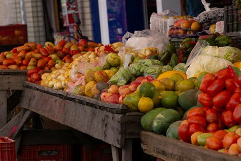 Foto de una feria libre con abundante fruta y verdura en exhibición y gente comprando
