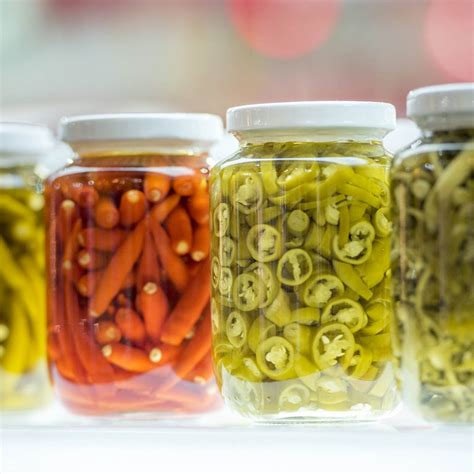 Visualización de frascos de conserva de champiñones listos para almacenar, con hojas de laurel y aceite cubriendo los hongos.