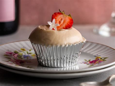 Fotografía profesional de cupcakes de frutilla frescos con una decoración de merengue y trozos de fruta natural.
