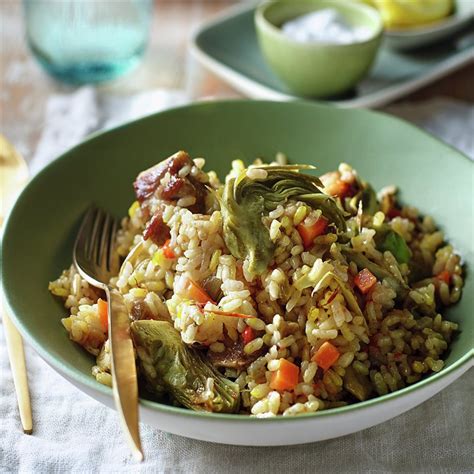 Plato de arroz con costillas de cerdo y alcachofas, mostrando una textura apetitosa y colores vibrantes.
