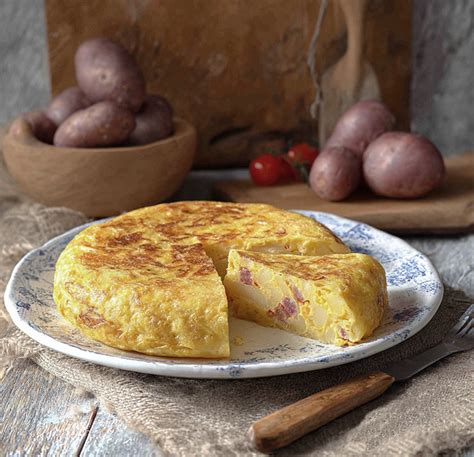 Una porción de tortilla española con longaniza servida en un plato, decorada con perejil