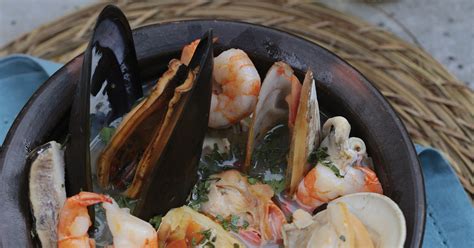 Paila marina servida en una paila de greda, mostrando la variedad de mariscos y pescado en un caldo humeante.
