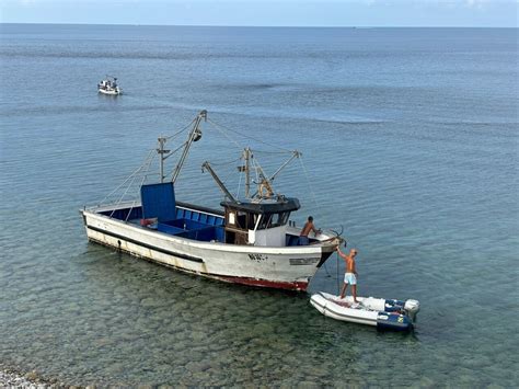 Barco pesquero artesanal en la costa, simbolizando la frescura y el origen local de los productos del mar.