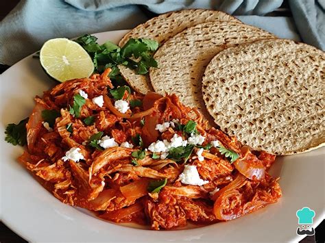 Plato de tacos de tinga de pollo servidos con aguacate, queso fresco y cebolla en escabeche