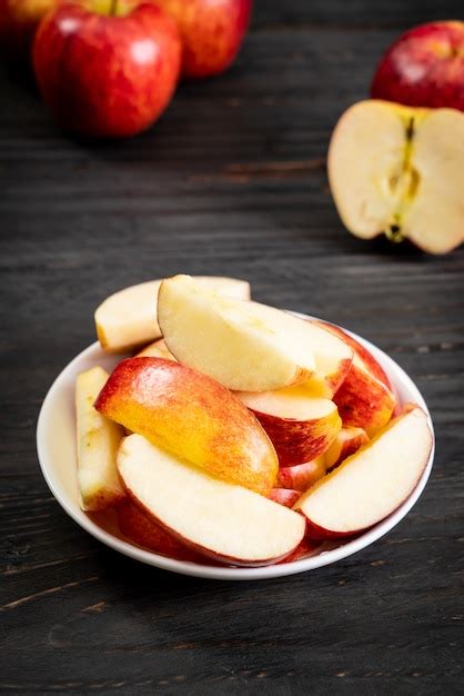 Manzana roja fresca y rodajas junto a un tazón con mascarilla facial y hojas verdes