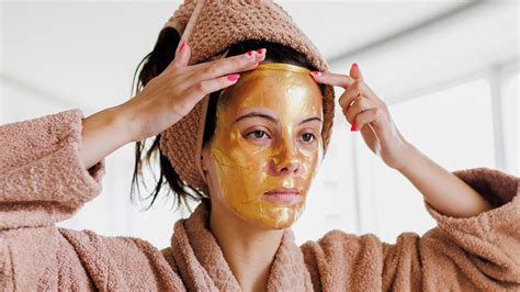 Manos aplicando mascarilla de manzana y miel en un rostro femenino