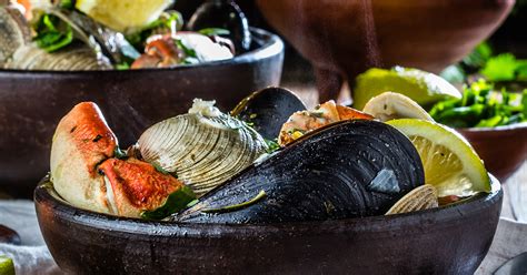 Ilustración de un caldillo de mariscos servido en un plato de greda, con vapor ascendiendo.