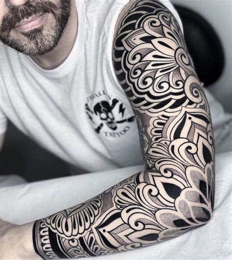 Fotografía artística de un tatuaje en el brazo que muestra manos rezando entrelazadas con un rosario