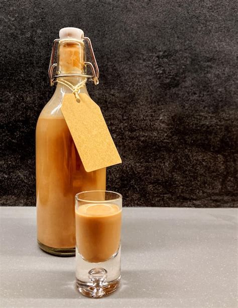 Botella de licor de chocolate casero servido en un vaso pequeño con detalles decorativos de cacao