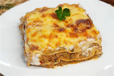 Fotografía de una bandeja de lasaña de verduras recién salida del horno con una capa dorada de queso