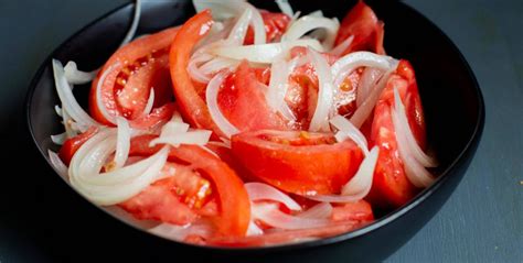 Ingredientes frescos: tomates, cebolla, limón y aceite de oliva, dispuestos para preparar la ensalada.
