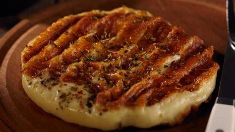 Imagen de una provoleta servida con chimichurri y ensalada fresca