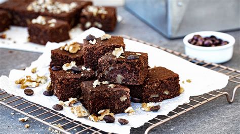 Imagen de brownie vegano de porotos negros cortado en cuadrados, espolvoreado con nueces picadas, sobre un plato.