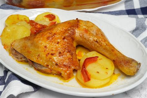 Fotografía de un plato servido de pollo a la plancha acompañado de patatas a lo pobre con pimientos y cebolla