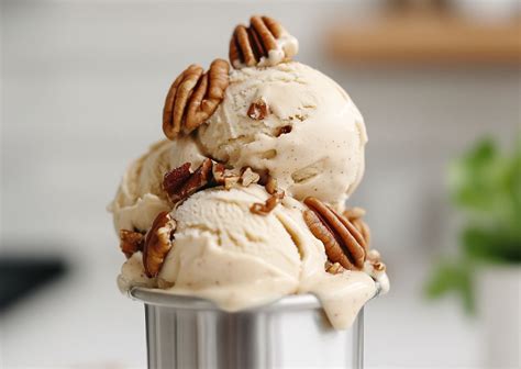 Foto de helado de mantequilla y nuez pecan en un bol, con nueces enteras alrededor