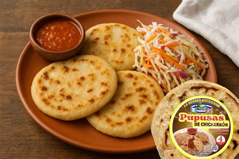 Fotografía de pupusas calientes servidas con curtido y salsa de tomate.