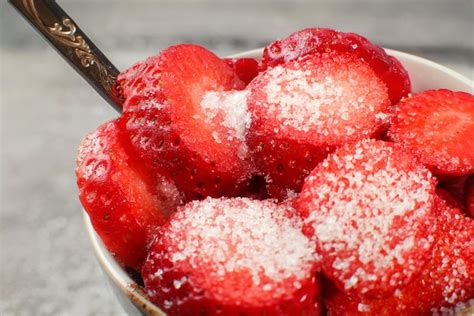Plato de fresas fritas espolvoreadas con azúcar glas y un tazón pequeño de salsa de chocolate al lado