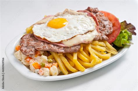 Fotografía de un Chivito uruguayo clásico servido en plato con guarnición de patatas fritas