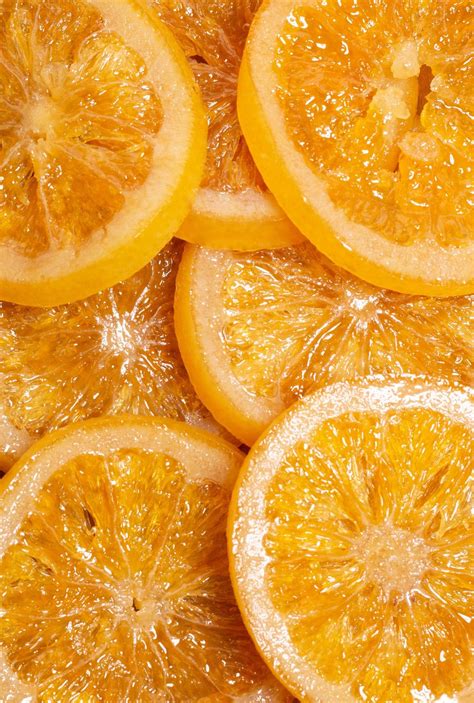 Imagen de rodajas de naranja confitada con textura brillante y traslúcida dispuestas en un plato