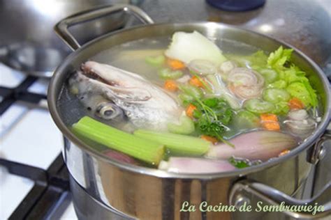 Esquema de los ingredientes básicos para un fumet: espinas de pescado blanco, puerro, cebolla y zanahoria sobre una mesa de cocina.