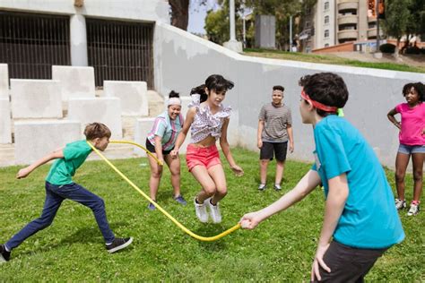 Fotografía antigua de niños jugando en un patio escolar recreando escenas de juegos tradicionales como el luche o el elástico