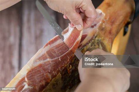 Mujer cortando jamón profesionalmente en un evento, con atención al detalle y precisión