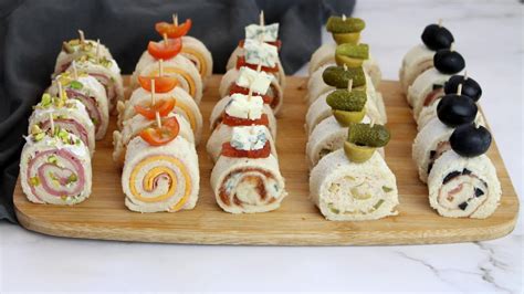 Fotografía de diversos rollos tipo sushi hechos con pan de molde y rellenos coloridos de vegetales y fiambres