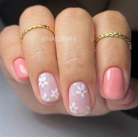 Uñas cortas en rosa pastel con delicados diseños florales en una uña