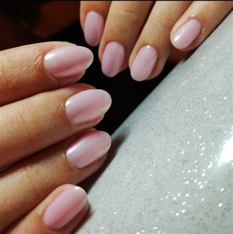 Primer plano de uñas cortas con acabado perlado en rosa pastel
