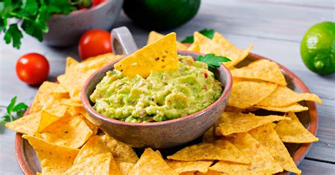 Plato de guacamole fresco con totopos y sus ingredientes principales al lado