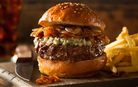 Primer plano de una hamburguesa gourmet con queso de cabra fundido, cebolla caramelizada y pan brioche tostado